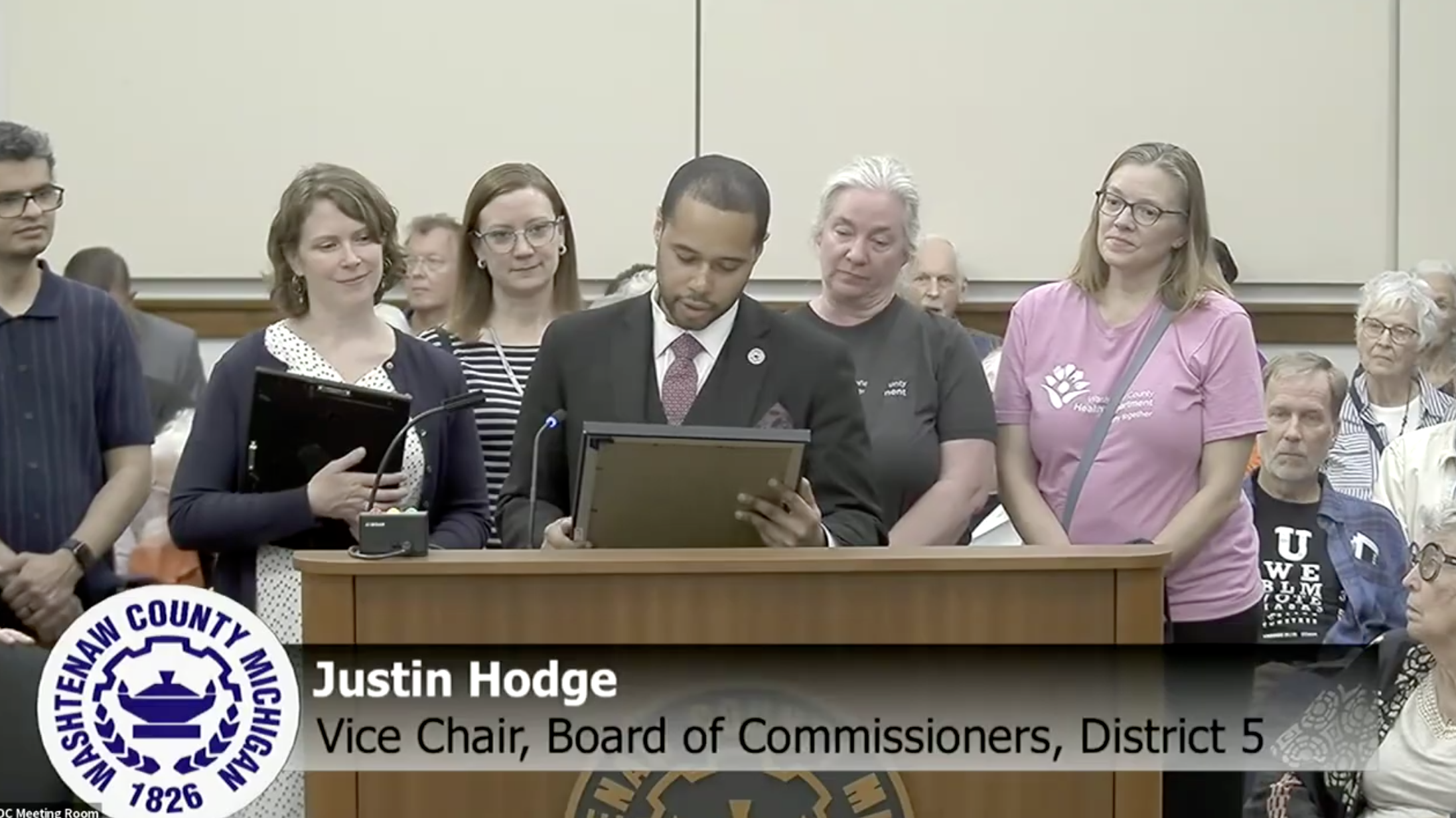 Commissioner Justin Hodge reads a resolution recognizing the Washtenaw County Health Department’s 2025 state accreditation during the May board meeting.